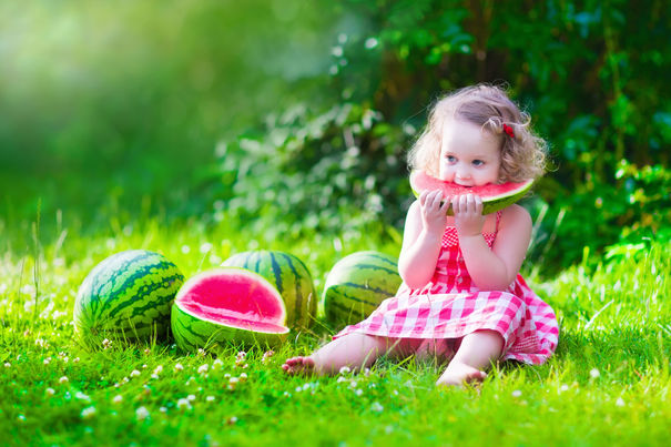 40479470 - child eating watermelon in the garden. kids eat fruit outdoors. healthy snack for children. little girl playing in the garden holding a slice of water melon. kid gardening.