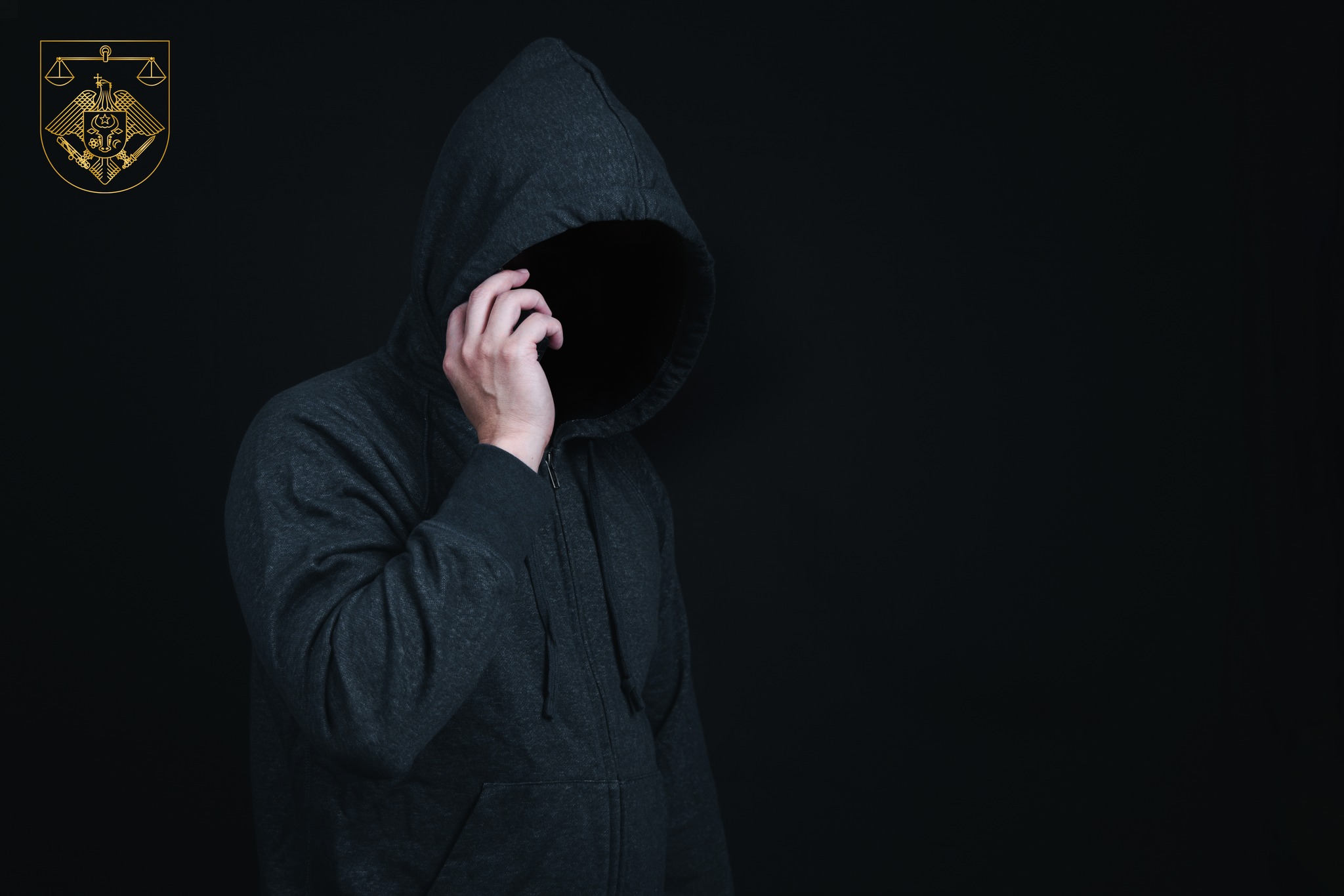 Man wearing hoodie is making phone call in dark background in concept of criminal or hacker try to lure or scam victim.