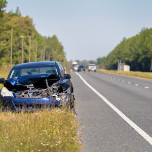 Dented car damaged after traffic accident parked on highway roadside. Transportation hazard concept